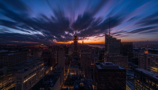 Dramatic Manhattan dusk with glowing Art Deco tower, streaking clouds and long-exposure city lights