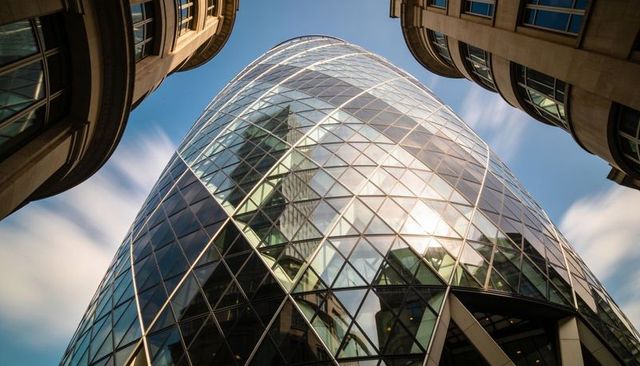 Dominating curved glass tower with diamond glazing and steel diagrid in urban canyon