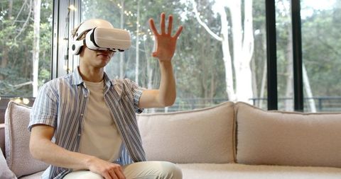 Man Wearing VR Headset Relaxing on Sofa with Nature View