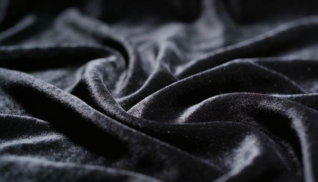 Black velvet draping and rippling closeup showing plush sheen and luxurious texture