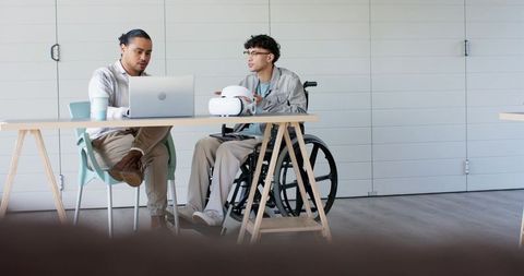 Collaborating on vr headset with colleague in wheelchair in modern minimalist workspace