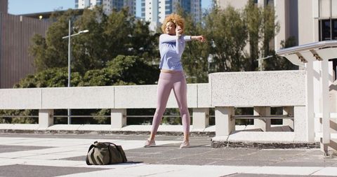 African American woman stretching on urban rooftop before outdoor workout