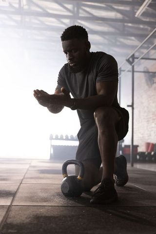 Focused athlete applying chalk before kettlebell workout in backlit warehouse gym