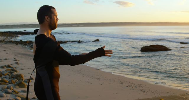 Surfer Stretching on Beach at Sunrise in Wetsuit - Download Free Stock Images Pikwizard.com