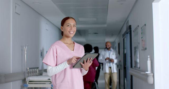 Smiling Nurse in Hospital Corridor Using Tablet - Download Free Stock Images Pikwizard.com