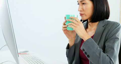 Businesswoman Enjoying Coffee While Working at Workspace