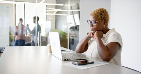 Professional Woman Multitasking with Laptop and Smartphone in Modern Office
