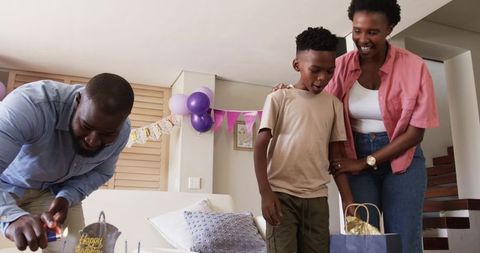 African American Family Celebrating Birthday at Home Parents Lighting Cake and Smiling