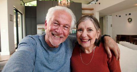 Happy Senior Couple Smiling on Sofa in Modern Living Room