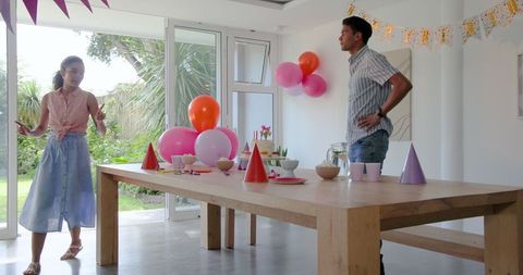 Couple decorating room for festive celebration with balloons and party setup