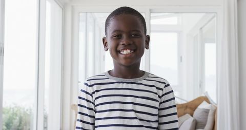Smiling Young Boy in Striped Shirt at Home with Bright Light - Download Free Stock Images Pikwizard.com