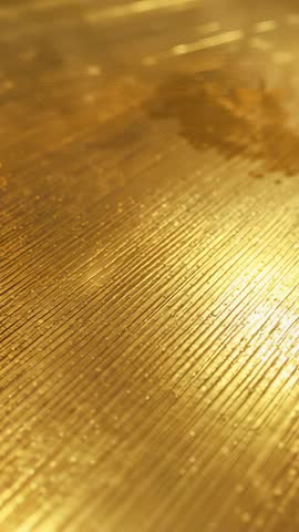 Shimmering gold ribs gliding under warm light, vertical studio video for texture details
