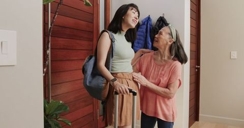 Asian Mother Greeting Daughter at Entryway with Warm Welcome