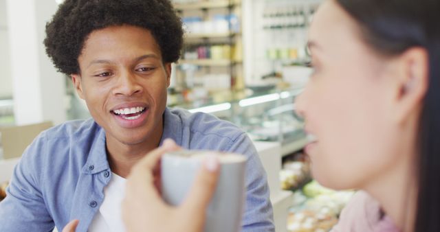 Young friends enjoying relaxed conversation over coffee inside a cozy cafeteria. Perfect for lifestyle articles, social media posts, or advertisements centered around friendship, coffee culture, or casual meetings.