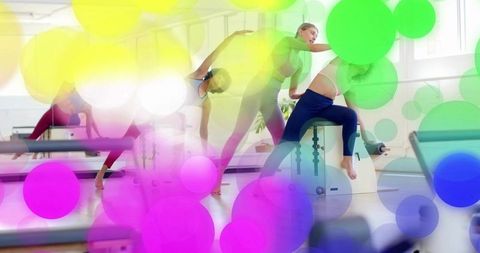 Women stretching on pilates barrel in bright studio with vibrant colorful bokeh overlays