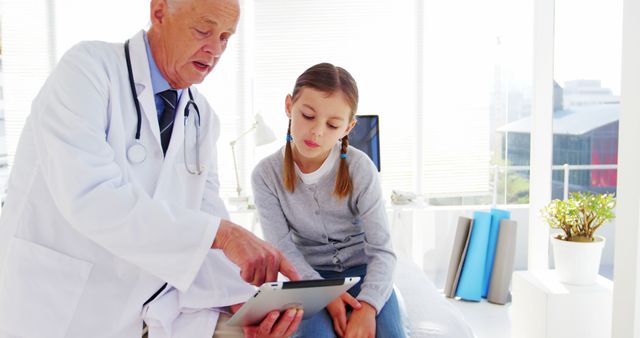 Senior Doctor Using Tablet to Explain Treatment to Young Girl in Bright Clinic - Download Free Stock Images Pikwizard.com