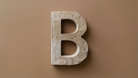 Stone letter b sculpture on matte brown background abstract design