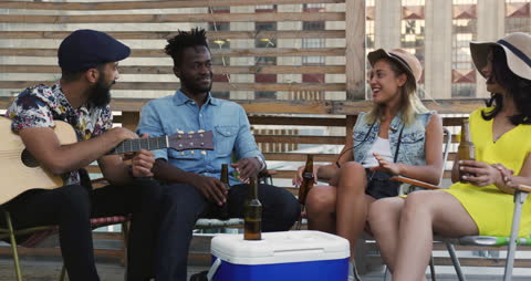 Diverse Friends Having Fun on Rooftop with Guitar and Drinks