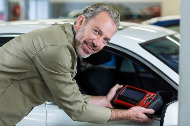 Portrait of mechanic using a diagnostic tool in repair garage