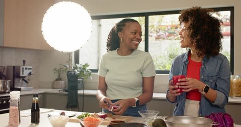 Friends cooking together on kitchen island preparing fresh vegetables for healthy meals