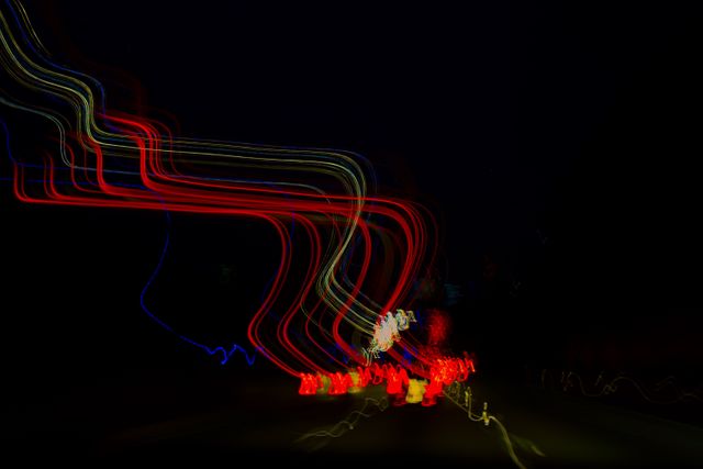 This image showcases vivid light trails captured at night in an abstract composition. Long exposure technique well-executed, creating red and blue streaks flowing through the dark background. Ideal for use in abstract art projects, wallpaper designs, creative backgrounds, and visual representations of motion and speed.