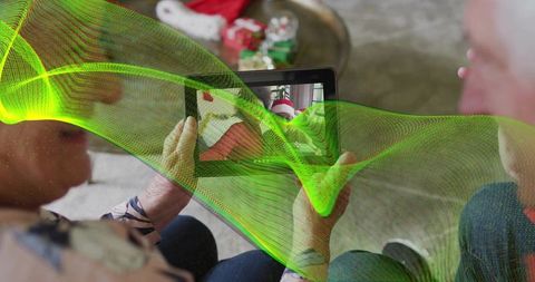 Grandparents holding tablet watching virtual holiday call with child in santa hat