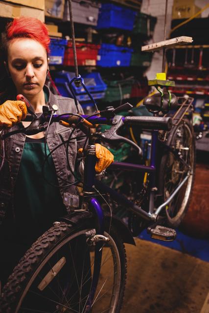 Female mechanic repairing bicycle in a workshop is great for content related to women in trades, bicycle maintenance tutorials, and promoting workshop and repair services. Useful for illustrating gender diversity and female empowerment in skilled professions.