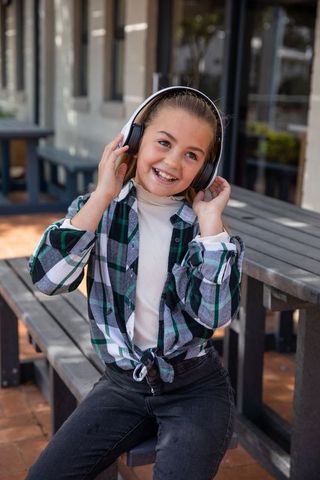 Smiling girl with wireless headphones outdoors enjoying music