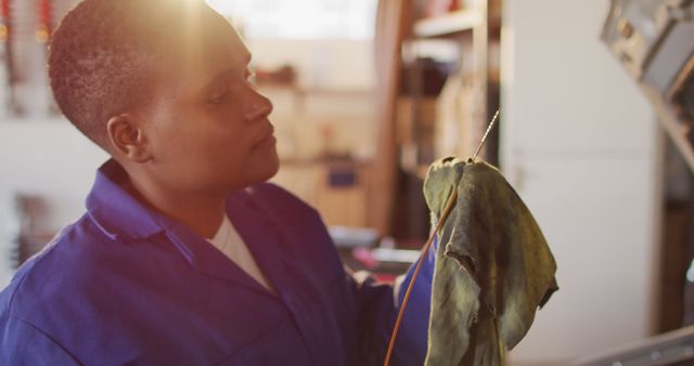 Image of african american female car mechanic checking oil level. working in car repair shop and running small feminine business concept.