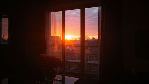 Warm sunset glowing through sliding glass doors, balcony silhouettes and cozy urban twilight