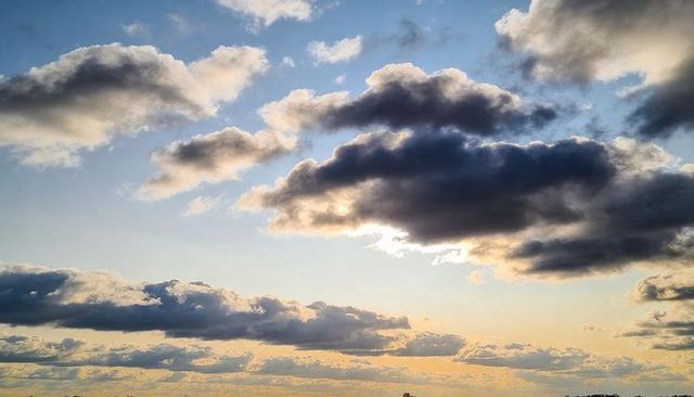 Dramatic Backlit Cumulus Clouds Over Golden Horizon at Sunset, Layered Expansive Skyscape