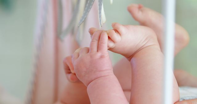 Delicate image capturing a baby's feet and hands playfully interacting. Ideal for parenting blogs, baby product advertisements, and websites focused on childhood and innocence. Shows tenderness and softness typical of a newborn, making it perfect for promotions in baby care and early childhood education.