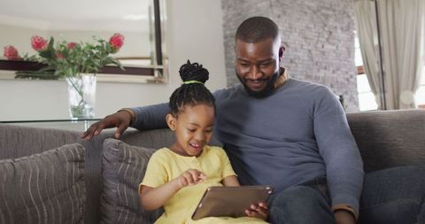 Father and Daughter Enjoying Tablet Couch Time