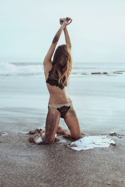 Woman Kneeling on Beach in Lingerie with Arms Raised - Download Free Stock Photos Pikwizard.com