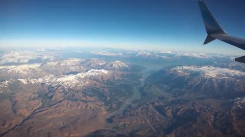 Winglet Gliding Over Snow-Capped Mountains and Winding River During Daytime Flight