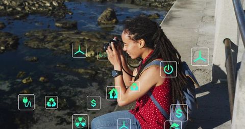 Young woman with dreadlocks capturing coastal shoreline on dslr with sustainability icons