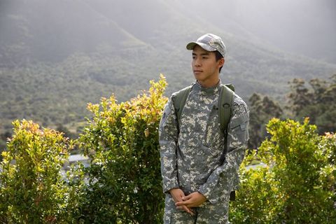 Asian soldier standing on mountain overlook wearing digital camo uniform and rucksack