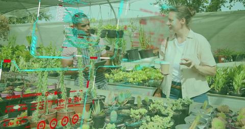 Nursery vendor reviewing tablet while customer holding coffee among potted succulents