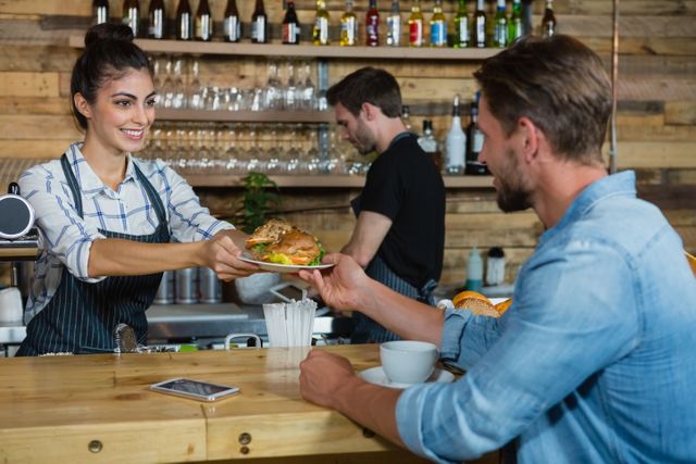 Waitress serving breakfast to man at counter in cafe