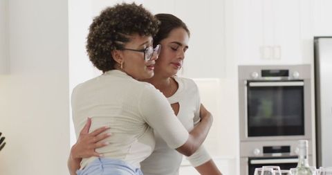 Two Women Embracing in Modern Kitchen Celebrating Friendship