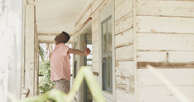 African american man stretching outside house on beach, copy space. Lifestyle, nature, relaxation, vacation, summer and leisure, unaltered.