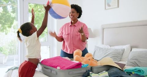 Afro Mother and Child Packing for Vacation with Beach Ball Fun