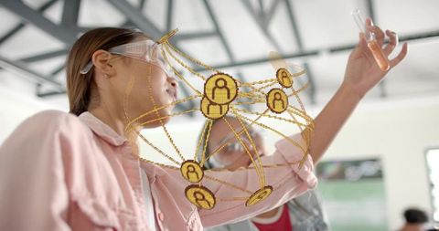 Young scientist examining test tube with augmented reality network overlay in science lab