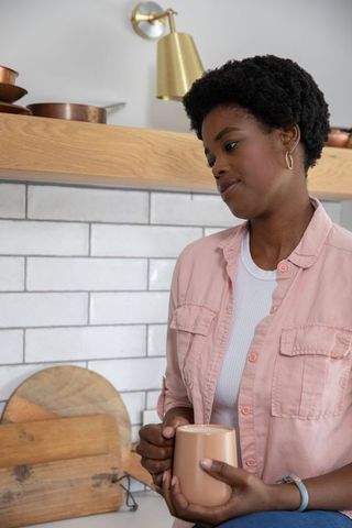 African american woman relaxing with mug in cozy modern kitchen