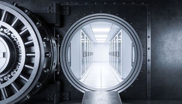 Circular vault door opening to secure data center aisle with illuminated server racks