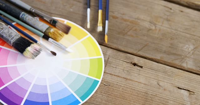 Paintbrushes with color swatch on wooden background