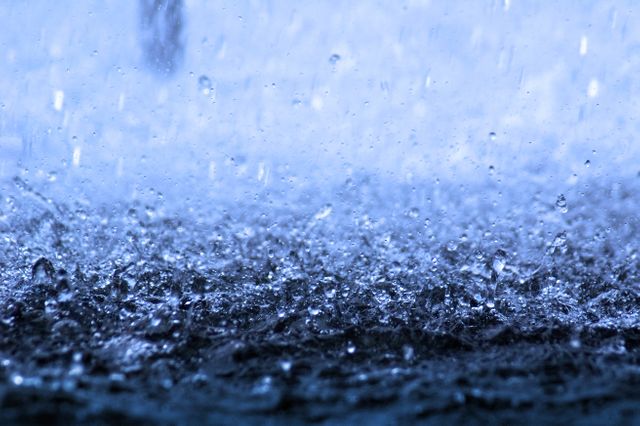 Heavy rainfall with visible water droplets creating splashes and ripples on a surface. Ideal for weather-related projects, nature content, and environmental documentaries. Use for backgrounds, illustrating stormy conditions, or adding a dramatic effect to your creative projects.