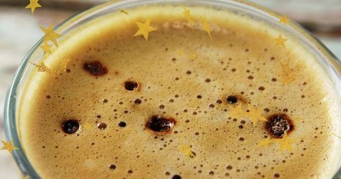 Macro espresso crema sparkling with gold star confetti, warm coffee closeup
