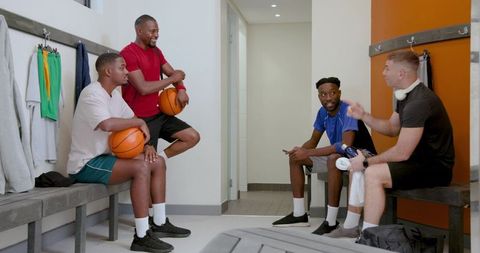 Locker room team huddle: diverse male basketball players resting and chatting