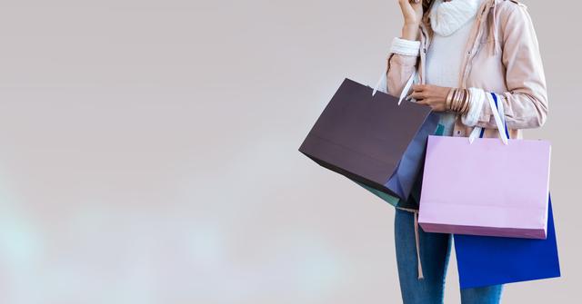 Shows woman wearing casual fashion, holding shopping bags and speaking on phone. Ideal for retail, fashion, shopping, and e-commerce themes. Suggests elements of convenience, modern living, and consumerism.